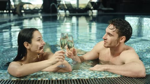 Beautiful Couple Clinking Glasses in Spa Pool. Man and Woman Flirting in Jacuzzi