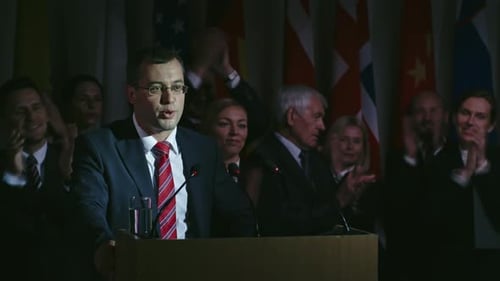 Man Giving Political Speech in Front of Flags