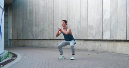 Fit Man Doing Squats Outdoors in Urban Environment