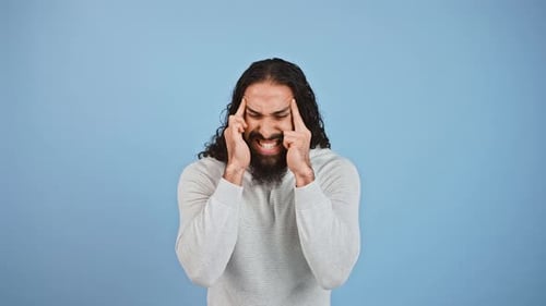 Man Massaging Temples on Blue Background