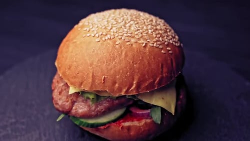 Hamburguesa fresca y apetecible que gira sobre fondo negro. Deliciosas hamburguesas asadas