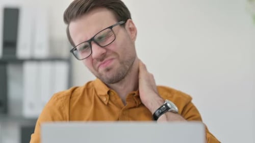 Close Up of Young Man with Laptop Having Neck Pain in Office