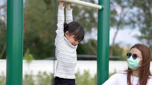 Joyful asian little girl playing exercise equipment in playground