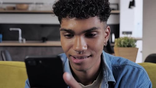 Young Adult Smiling Using Smartphone at Home