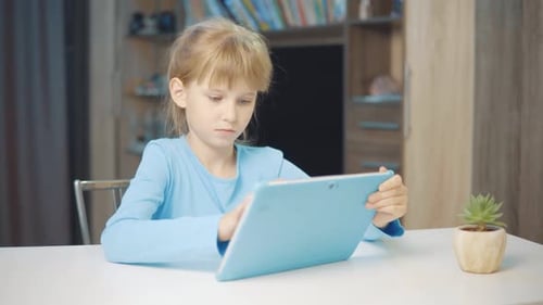Child Uses Tablet Indoors at Table
