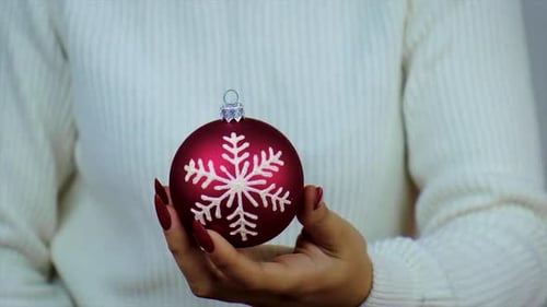 Woman Holding Red Christmas Ornament with Snowflake