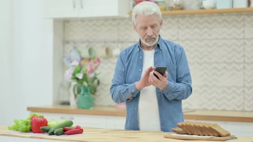 Senior Man Uses Phone in Bright Kitchen