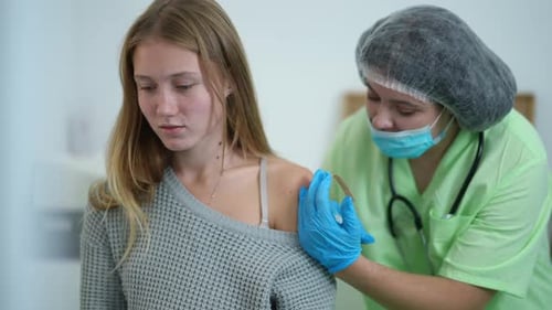 Young Caucasian Beautiful Woman Feeling Pain As Nurse Injecting Coronavirus Vaccine Jab in Shoulder
