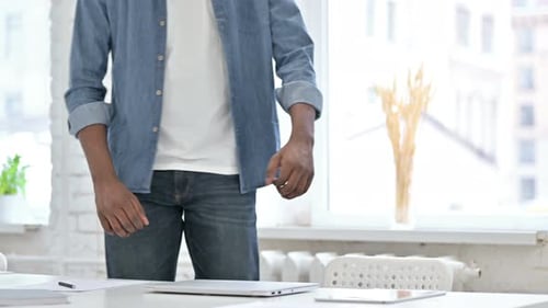 Young Adult Opens Laptop and Types at Desk
