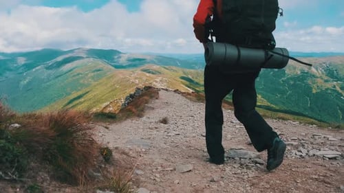 Tourist with a Backpack Goes Down Along the Stone Mountain Trail on the Hill