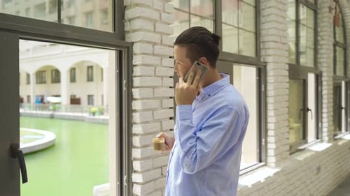 Young Adult Chats on Phone Indoors by Window