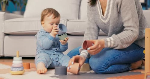 Baby Stacking Colorful Cups with Mother at Home