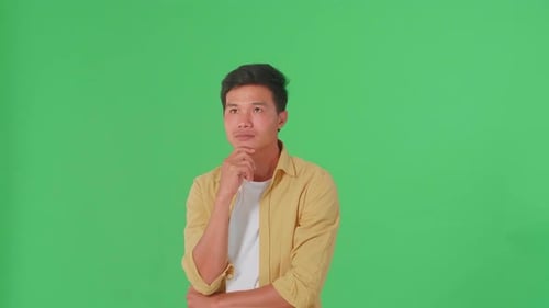 Young Asian Man Thinking About Something Then Raising Her Index Finger In Green Screen Studio