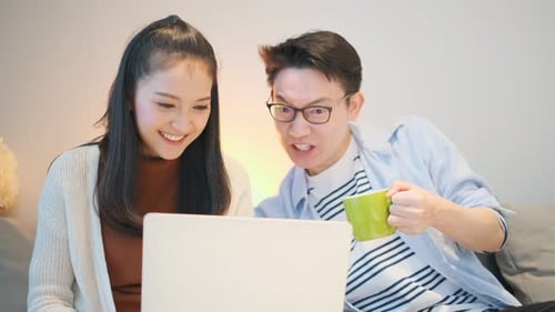 Cheerful Couple Sharing Laptop at Home