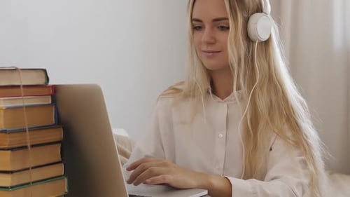 Woman with Headphones Typing on Laptop at Home