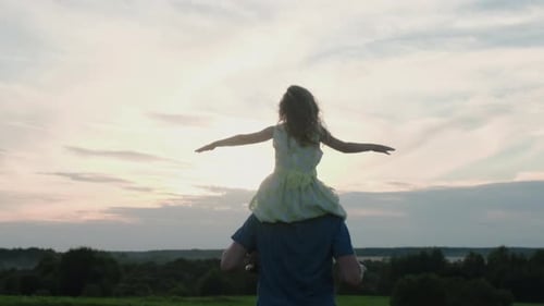 Father and Daughter Playfully Enjoying Sunset in Field