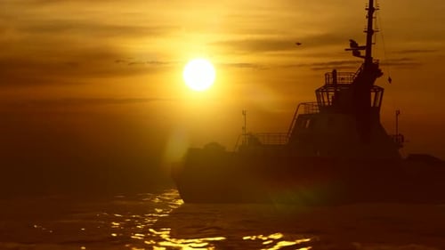 Tugboat Sailing at Golden Sunset Over Ocean