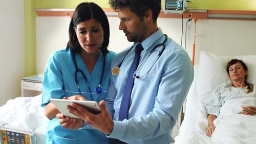 Medical Professionals Reviewing Tablet in Hospital Room