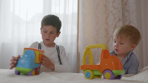 Two Cute Children Play with Toy Trucks