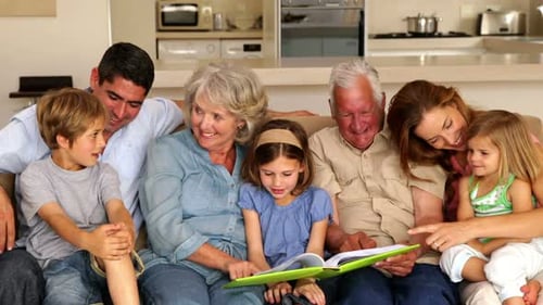 Família estendida olhando para o álbum de fotos juntos no sofá