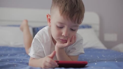 Boy Lying on Bed Watching Mobile Phone