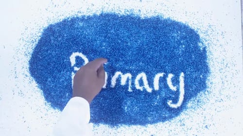 Hand Writes Primary on Pile of Blue Shavings