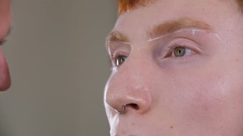 Brow Master Drawing Guiding Lines on the Eyebrows of His Ginger Male Client