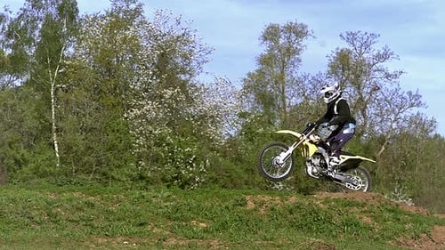 Motocross Rider Jumps Hill in Rural Landscape