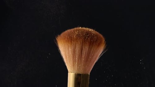 Schimmerpuder Coming Down auf Make-up-Pinsel auf schwarzem Hintergrund