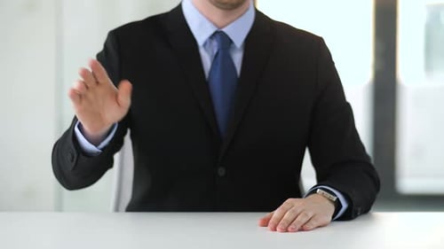 Businessman Gesturing While Sitting at a Desk