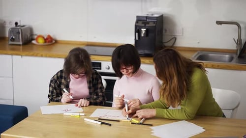 Children Drawing Together at Kitchen Table with Adult