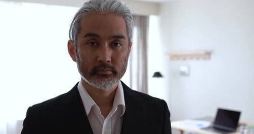 Asian man looking on camera inside modern office