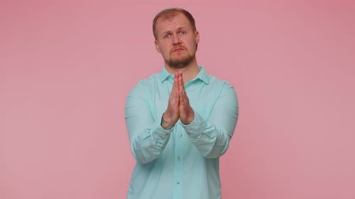 Man Pleading with Hands Together on Pink Background