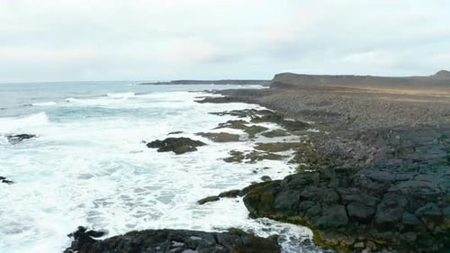 Rocky Shoreline Of Beach And Peninsula Hit By Foamy Waves In Iceland. - aerial