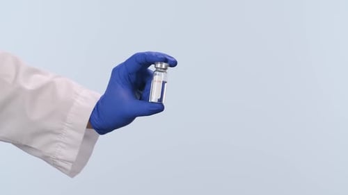 Gloved Hand Holds Sealed Vaccine Vial in Lab