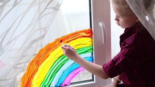 Little Girl Painting a Colorful Rainbow on Window
