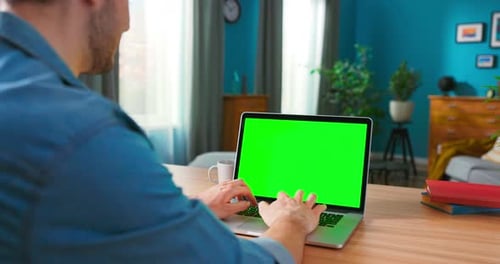 Foto sobre el hombro de manos de hombres escribiendo en una computadora portátil con pantalla verde