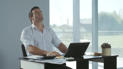 Adult Man Stretching at Desk During Daytime