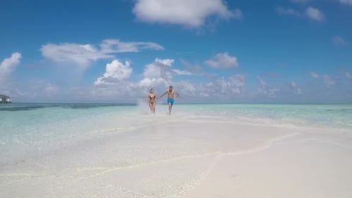 Couple Runs on Tropical Beach, Hand in Hand