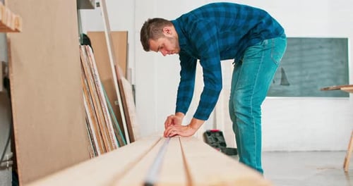 Adult Man Measuring Wood in Workshop