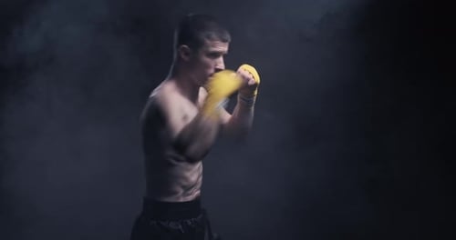 Muscular Man Shadow Boxing in Smoky Dark Setting
