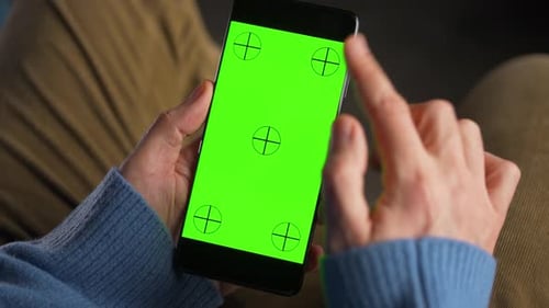 Man Using Smartphone with Green Mockup Screen in Vertical Mode