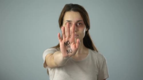 Woman with Bruises Raises Hand with Message
