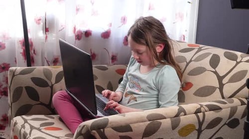 Young Girl Typing on Laptop Computer at Home