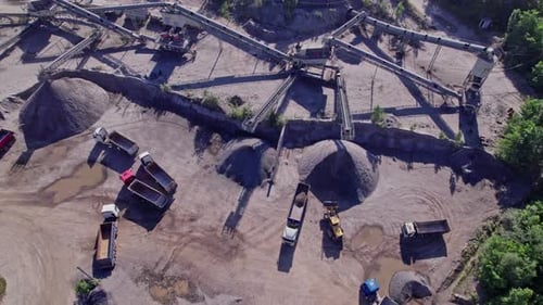 Excavators and Tractors Load Crushed Stone and Rock Into Dump Trucks