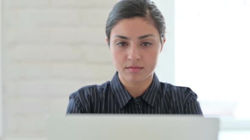 Nahaufnahme einer indischen Frau mit Laptop beim Husten