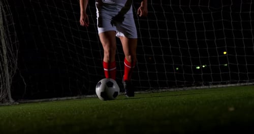 Soccer Player Kicking Ball on Field at Night