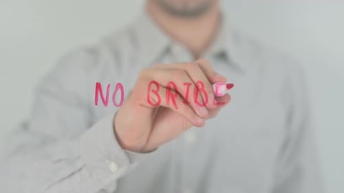 Man Writing 'No Bribes' on Glass Surface