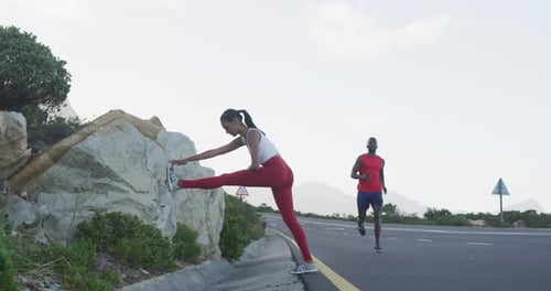 Diverse fit couple exercising stretching and running on a country road