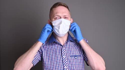 Man takes off face mask in blue gloves